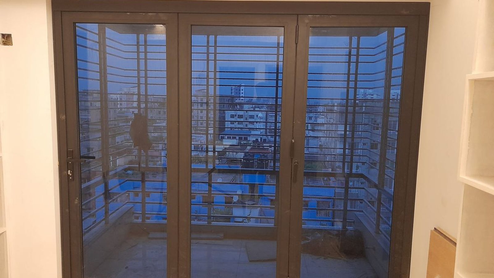 Bronze three-panel aluminium door opening onto a balcony, as installed