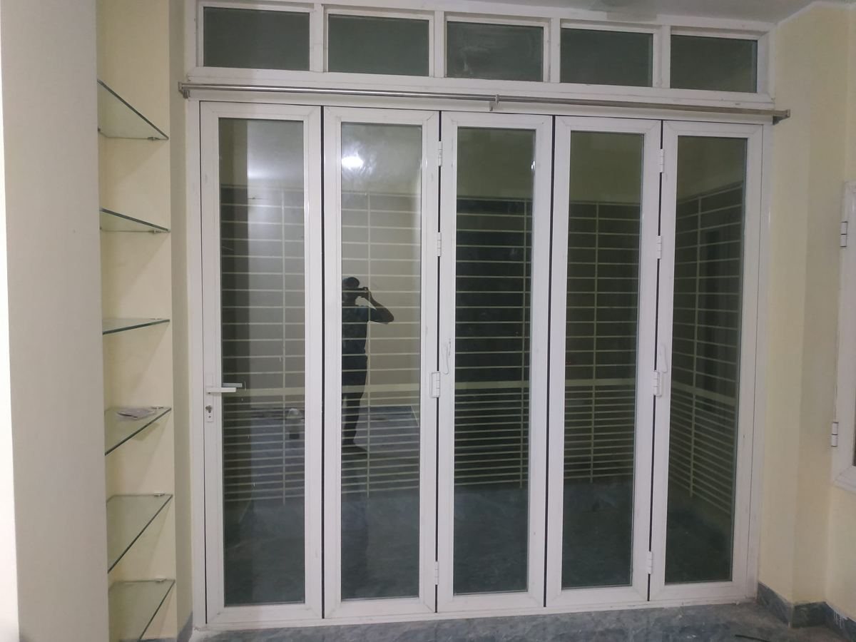 White aluminium five-panel folding door with a glazed transom above