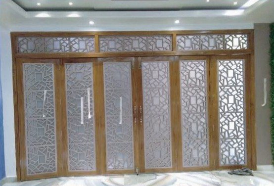 Folding partition with laser-cut jali panels in a wood-finish frame